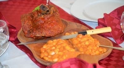 Ciolan de porc cu iahnie de fasole, servit pe tocător de lemn